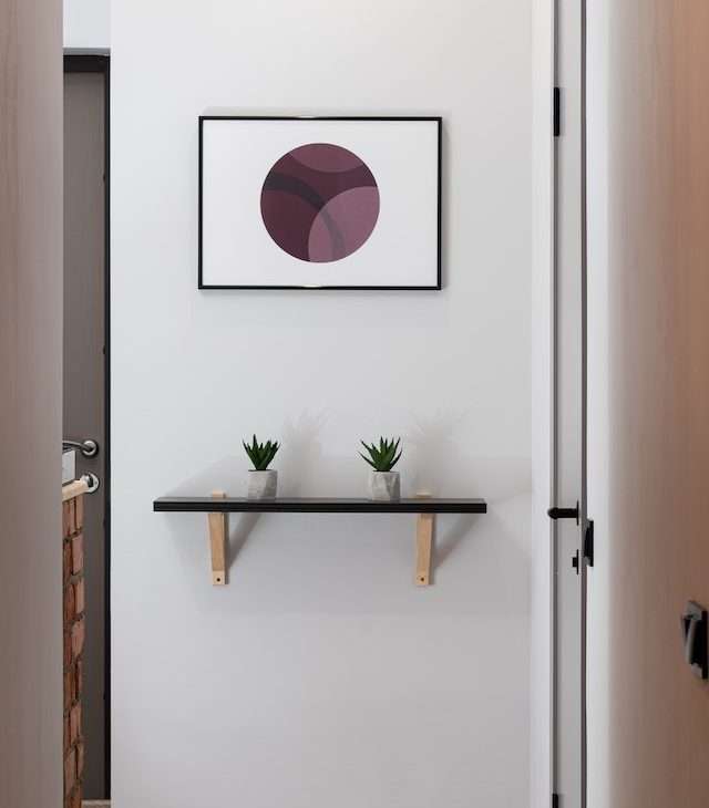 A white wall with shelf and abstract painting